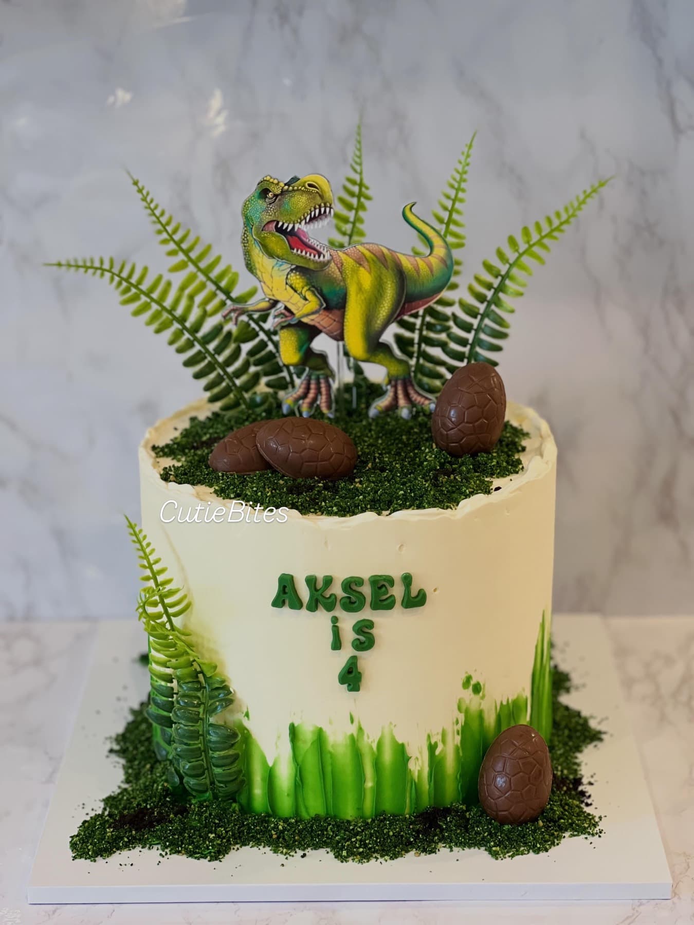 T-Rex jungle birthday cake with ferns, chocolate eggs and green drip — Cutie Bites, Orpington