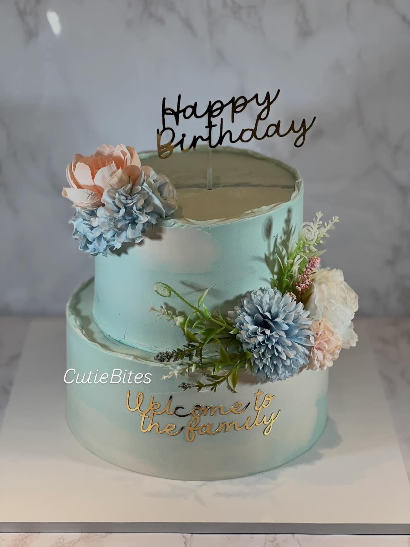 Two-tier welcome to the family cake with aqua watercolour buttercream and blue flowers — Cutie Bites, Orpington