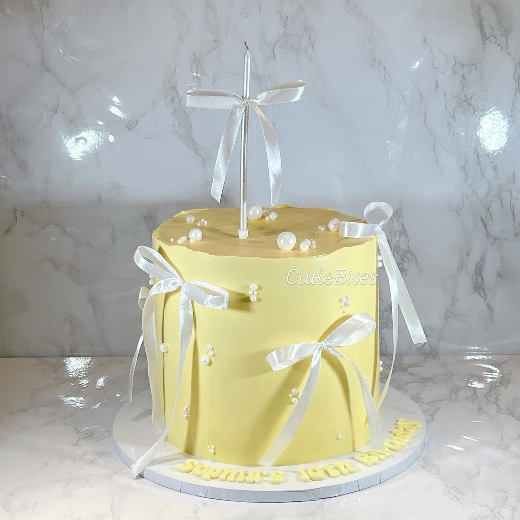 Yellow birthday cake with satin bows and pearl details — Cutie Bites, Orpington